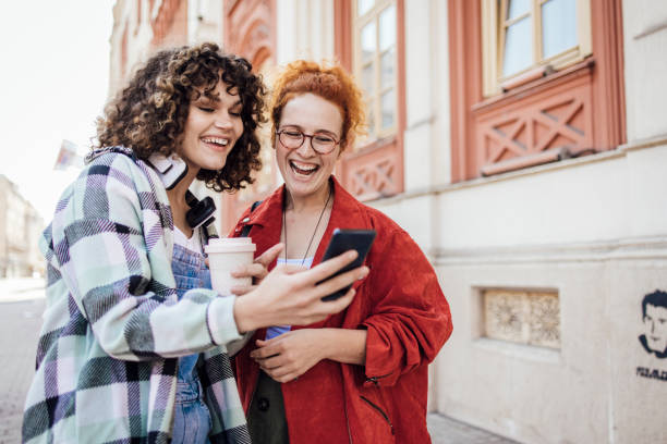 Two girls using smartphone on the move and having fun