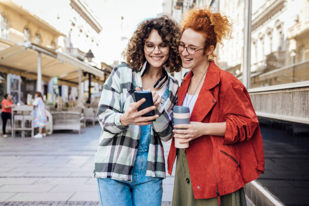 istock Two happy girls enjoying coffee while walking down the street 1384369470