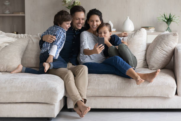 istock Family enjoy funny mobile application relaxing on couch at home 1384369480