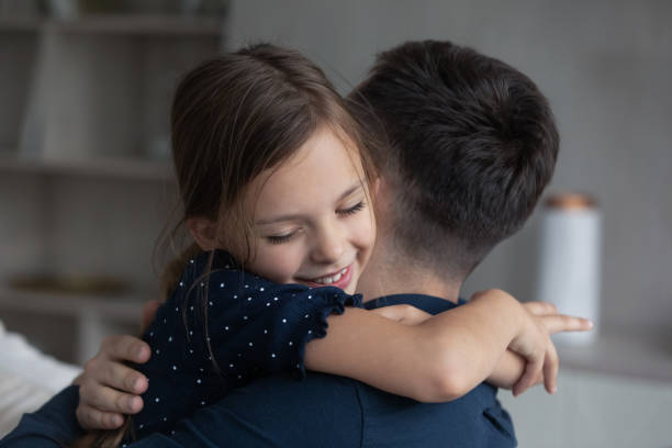 istock Daughter tightly cuddling her beloved daddy, close up 1384369487
