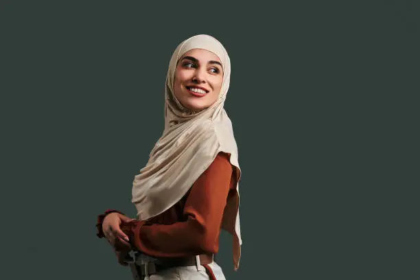 Smiling modern, beautiful muslim woman on gray background. Copy space.