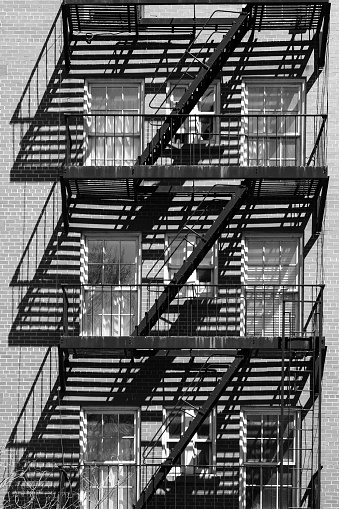 New York City fire escape photographed in black and white enhancing shadows.