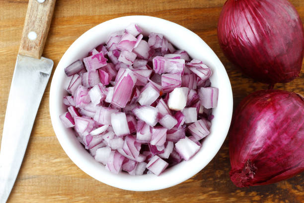 chopped raw red onion in white ceramic bowl over rustic wooden table chopped raw red onion in white ceramic bowl over rustic wooden table. Close up view spanish onion stock pictures, royalty-free photos & images