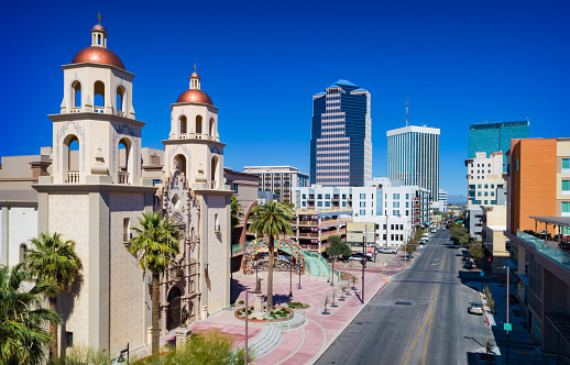 Downtown Tucson scene with skyscrapers in the background and the Cathedral of Saint Augustine in the foreground.
