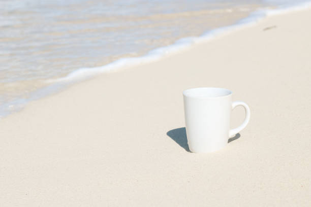 istock White coffee cup on the sandy beach in tropics 1384421770