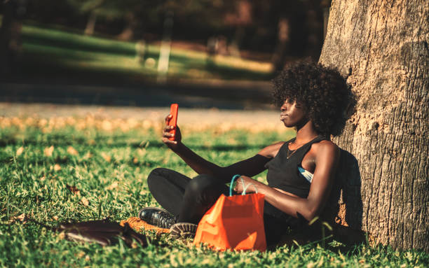 istock Black girl in a park using cellphone 1384422389
