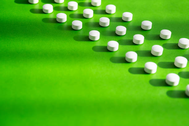 istock White pills or vitamin capsules pattern on green background, copy space. Dietary supplement supports for health. 1384424529