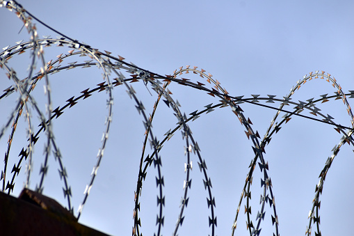 The close-up shot of barbed wire and a dark fence against the sky.