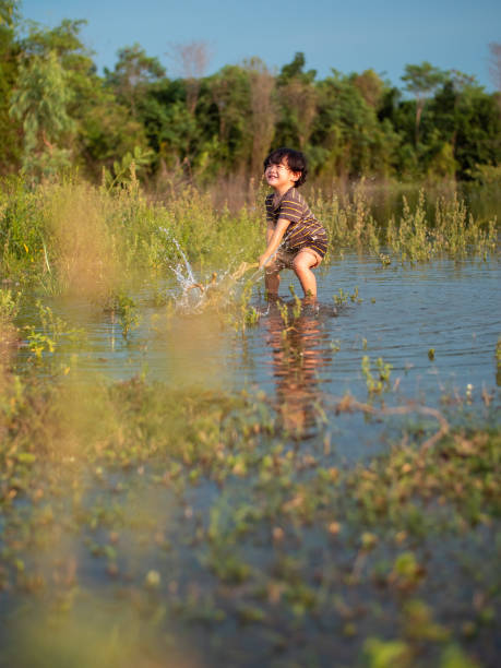 Tribal women engage in traditional fishing using Jakoi, a bamboo fishing tool, in a shallow wetland in Baksa, India on July 12, 2025.