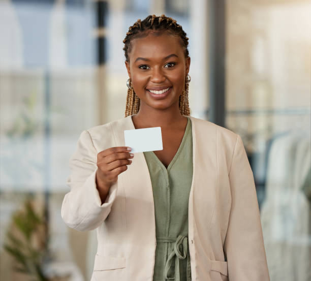 retrato de una joven empresaria mostrando su tarjeta de visita en una oficina moderna - smiling business card horizontal women fotografías e imágenes de stock