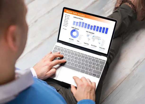 Photo of Man viewing website traffic analytics data on laptop computer