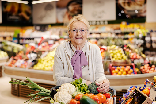 Mujer mayor comprando verduras orgánicas en el supermercado y sonriendo a la cámara. photo