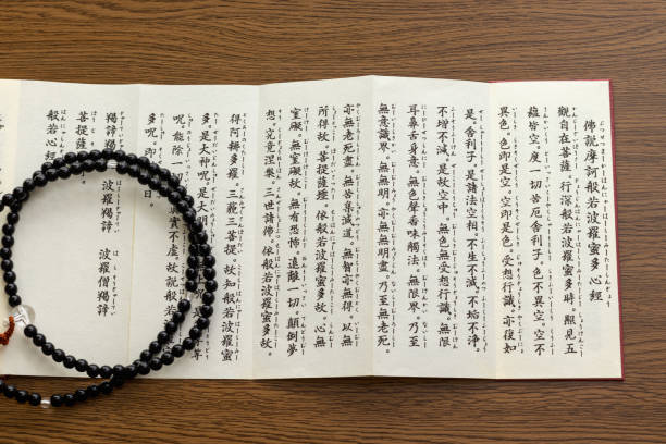istock Buddhist sutra and rosary on a wooden desk 1384456119