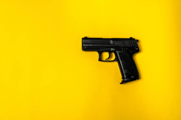 istock Short black gun on a yellow background. 1384468113