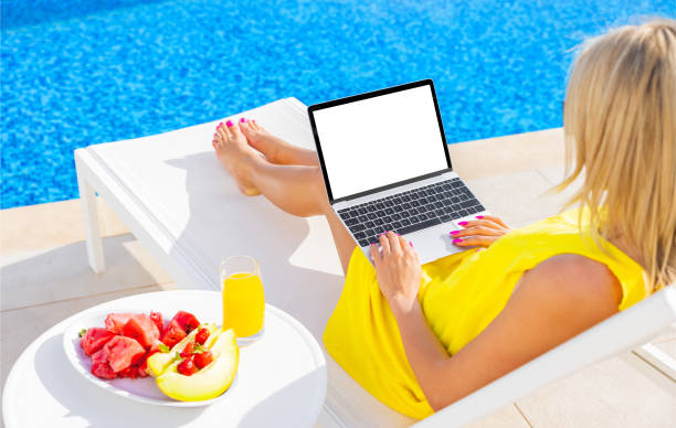Woman using laptop by the pool