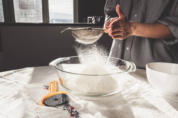 istock Woman sifting flour into a mixing bowl while preparing for baking in her kitchen 1384473013