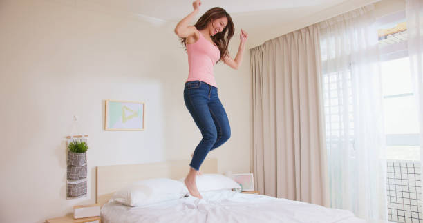 istock Young woman jump on bed 1384477073