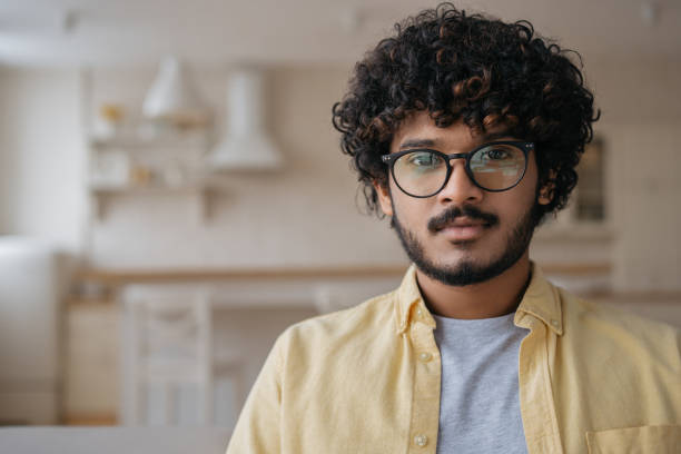 Pensive Indian man wearing eyeglasses looking at camera stock photo