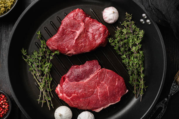 istock Raw beef meat steak with herbs, on black wooden table background, top view flat lay 1384482197