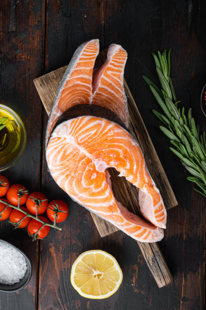 istock Fesh raw trout fillet with herbs, on old wooden table, top view 1384492545
