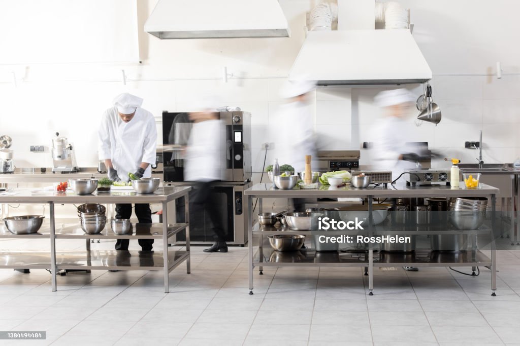 Chef cooks working in professional kitchen Chef cooks working in professional kitchen. Chefs hurry up, actively cooking meals for restaurant. Long exposure with motion blurred figures Blurred Motion Stock Photo