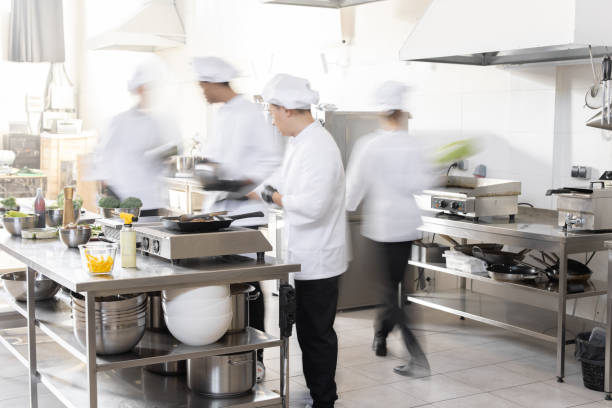 Chef cooks working in professional kitchen Chef cooks working in professional kitchen. Chefs hurry up, actively cooking meals for restaurant. Long exposure with motion blurred figures commercial kitchen stock pictures, royalty-free photos & images