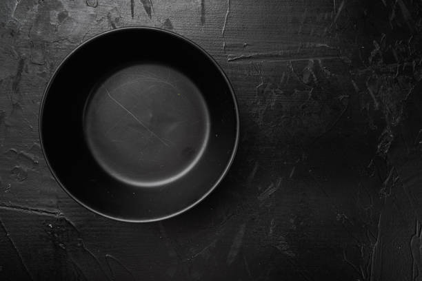 istock Empty black bowl, with copy space for text or food, with copy space for text or food, top view flat lay , on black dark stone table background 1384495108