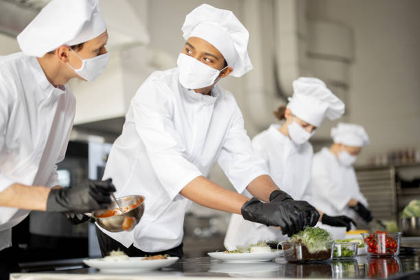 istock Group of cooks finishing main courses while working together in the kitchen 1384497562