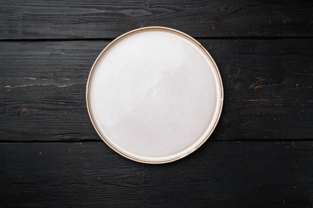 istock Empty ceramic plate with copy space for text or food with copy space for text or food, top view flat lay , on black wooden table background 1384504863