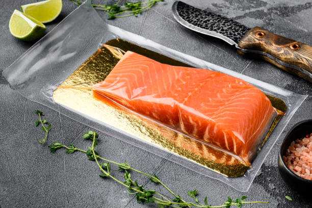 Fresh raw salmon fish steak in vacuum pack, with herbs, on gray stone table background, with copy space for text Fresh raw salmon fish steak in vacuum pack set, with herbs, on gray stone table background, with copy space for text vacuum packed stock pictures, royalty-free photos & images