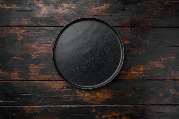 istock Black plate, on old dark  wooden table background 1384515199