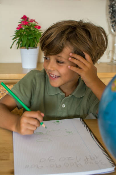 istock Little Boy In The Living Room Doing Homework. 1384516319