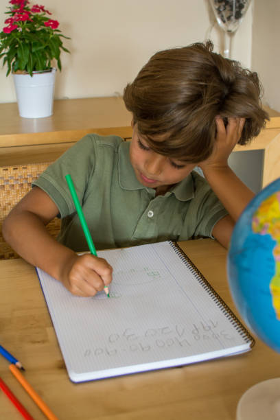 istock Little Boy In The Living Room Doing Homework. 1384516327
