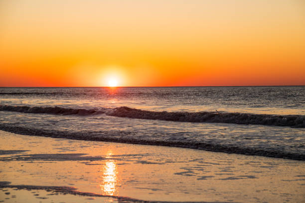 Sunset in beautiful orange colors on a soft sandy beach wich calm waves.