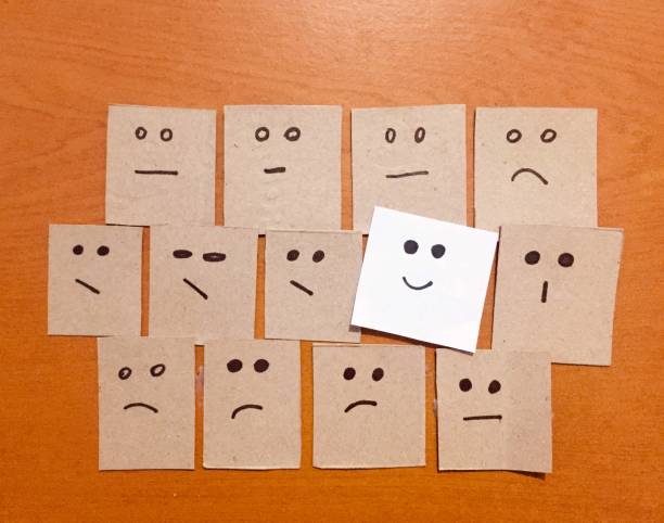 istock Concept for a positive attitide with small office notes on the wall magazine with multiplefaces and one of that stands out with a smile. 1384524261