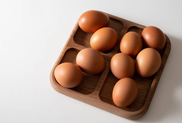 istock Top view brown eggs in wooden bowl on white table. 1384524306