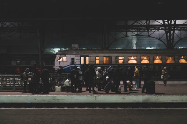 People waiting for a train in Lviv, Ukraine Lviv, Ukraine - March 4, 2022: People with luggage stand on a train station platform at night in Lviv, Ukraine refugee photos stock pictures, royalty-free photos & images