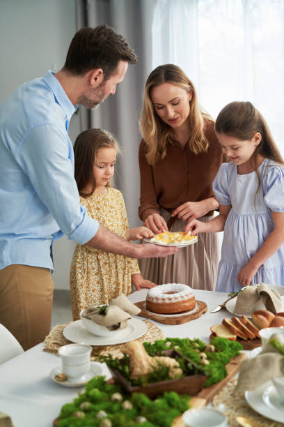 istock Vertical image of cheerful caucasian family of four sharing with egg during easter dinner 1384525687