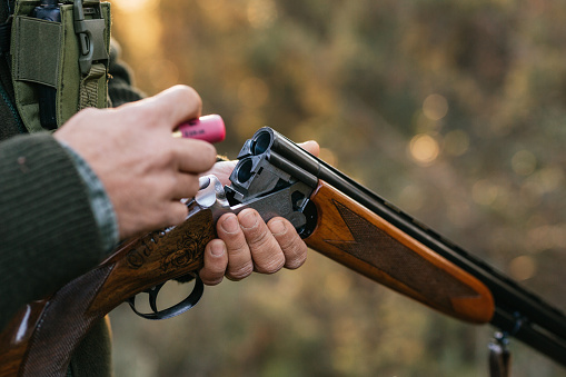 Hombre cazador cargando su arma mientras caza al aire libre. photo