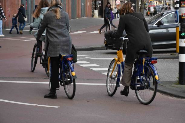 Downtown Amsterdam In North Holland Europe, Road Traffic, Building Exterior, People Walking, Riding Bicycle, Waiting For Traffic Light Scene During Autumn Season
