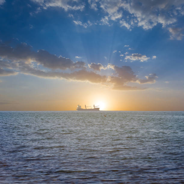 istock alone cargo ship silhouette in far sea at the sunset 1384528241