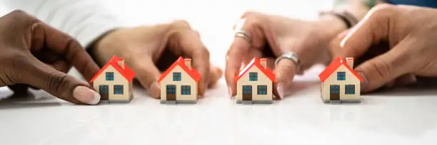 Homeowner Association By People Holding House Model On White Surface