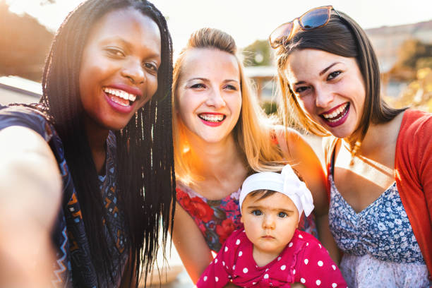 istock Multi ethnic female friends with kids taking selfies 1384533583
