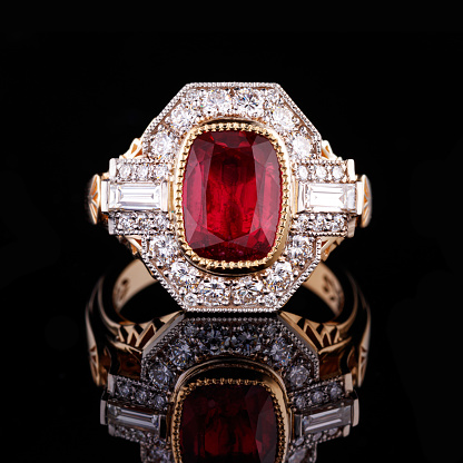 Beautiful yellow gold ring with a ruby on a black background close-up