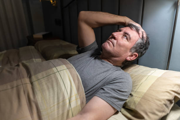 Man with insomnia lying in bed and pensively looking at the ceiling. Man with insomnia lying in bed and pensively looking at the ceiling. sleeping pill stock pictures, royalty-free photos & images