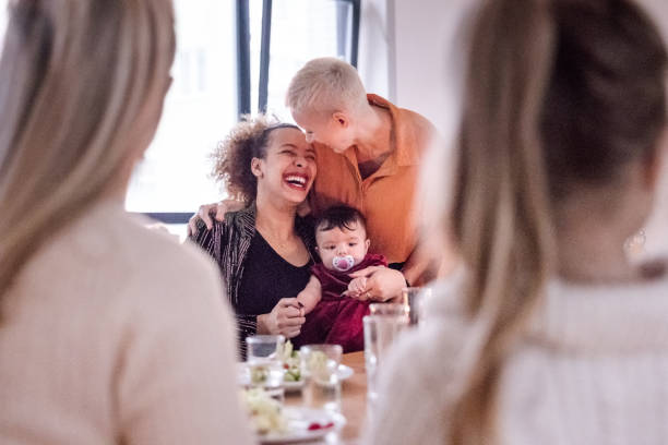 Beautiful couple with girl at dinner table with friends Lovely female couple with their daughter sitting at dinner table with friends. Beautiful couple with girl at dinner table. gay dinner table stock pictures, royalty-free photos & images