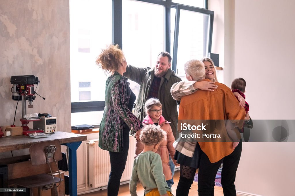 Couple welcoming guests for diner party at home Group of friends greeting each other at home. Lesbian couple welcoming guests at dinner party indoors. Family Stock Photo