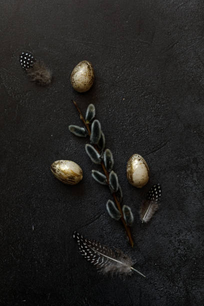 istock Happy Easter concept. Preparation for holiday. Golden decorated easter eggs willow feather on trendy grunge scratched dark black shale background. Simple minimalism flat lay top view, copy space 1384567940