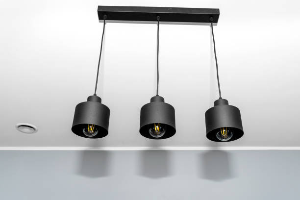 istock Modern chandeliers with tube shaped LED bulbs, covered with matt black paint, three bulbs visible. 1384570198