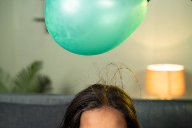 髪を引き付けるために風船を置いて遊んでいる子供たちのクローズアップショット - 静的にしがみつく家庭科学の実験と学習の概念 - balloon child people color image ストックフォトと画像